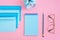 Blue correspondence envelopes, clock and notebook on pink background with copy space. Back to school or work concept