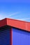 Blue Corrugated Steel Wall with Aluminium louver and red roof of Warehouse Building against blue sky background