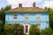 Blue country house with white windows surrounded by garden