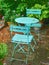 Blue courtyard metal chairs and table in serene, peaceful, lush, private backyard at home on a summers day. Patio