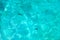 Blue crystal clear sea water texture background, turquoise transparent ocean surface close up, sun light rays reflection