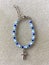 Blue Crystal Glass Beaded Bracelet with Cross Charm on Textured Background