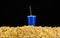 Blue cup with tube installed on scattered popcorn isolated on black background