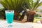 Blue Curacao Beach Cocktail with fresh lemon standing on a landing stage, with palm in background