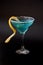 Blue Curacao, a refreshing liqueur with lemon zest and ice in a tall glass with sugar rimmed against a black background