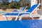 Blue cushion deckchair on the edge of a swimming pool in summer