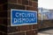 Blue Cyclists Dismount sign on brick wall outside