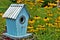 Blue decretive birdhouse surrounded by black eyed Susan flowers