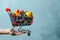 Blue delight Hand holding shopping cart with vibrant fruits and vegetables