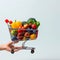 Blue delight Hand holding shopping cart with vibrant fruits and vegetables