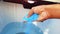 Blue detergent powder in hands and adding it in water in washing machine with motion blur