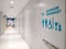 Blue disabled wheelchair and a family restroom sign on white modern wall in clean corridor inside of shopping mall