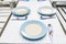 Blue Dishes with Spoons and Forks on Dining Tables Outdoor Restaurant Setting with Wedding Decorated.  Romantic Concept