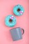 Blue Donuts with icing and coffe cup on pastel rose background. Sweet donuts.