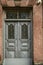 Blue double wooden door with carved details and openwork wrought iron bars on the Windows doors on the facade of a stone building