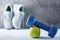 Blue dumbbell on a green Apple, light sneakers on a gray background
