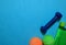 Blue dumbbell, Green and orange tennis ball, and bottle indicating workout plan on blue background.