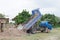 Blue dump truck unloading soil at construction site