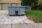 A blue dumpster filled with construction debris in the driveway of a yellow house in front of the garage doors