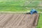 Blue dusty tractor with seedbed cultivator standing at the edge
