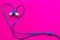 Blue in ear headphones arranged in heart shape on purple background and copy space