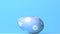 Blue easter egg rolling across blue background