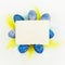Blue Easter eggs, bright colorful feathers and paper card on white background. Flat lay, top view