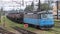 Blue electrical locomotive with a oil tank railway wagons driing at a railway station. Transportation cargo of refinery. Railroad