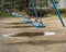 Blue empty swing set with a puddle in the background.