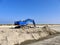 Blue excavator on pile of sand