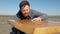 A blue-eyed carpenter with a beard and mustache against a blue sky touches the surface of the table, made by him by hand