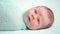 Blue-eyed newborn baby lying and looking around in wonder