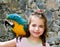 Blue eyes child girl with yellow parrot