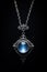 Blue fantasy necklace pendant - silver chain - black background - blue glow - blue gem