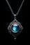 Blue fantasy necklace pendant - silver chain - black background - blue glow - blue gem