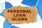 On the blue financial charts is a piece of cardboard that says - Personal Loan Scams