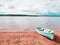 Blue fishing boat anchored on beach sand of lake. Smooth level