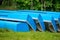 Blue fishing boats stacked on green grass. Pile of blue boats