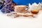 Blue flowers, cup of coffee cocoa, honey, biscuit , bowl on white dirty background, spilled with powder and milk foam