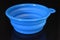 Blue folding and multifunctional rubber plate, a bowl with a plastic edging on a black glossy surface.