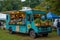 A blue food truck is parked in a spacious field, serving delicious meals to hungry