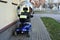 Blue four wheeled mobility scooter- electric wheelchair parked outside a house