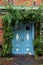 Blue front door in a historic house with climbing plants at the
