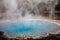 Blue geyser basin with smoke boiling in dry environment