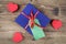 Blue gift box with red ribbon, blank gift tag and and red hearts on wooden background.