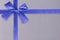 Blue gift ribbon and knot on a shiny textured pattern in background.