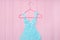 Blue girls stylized dress from stars confetti hanging on red trempel on pink wooden background. Fashion concept