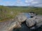 Blue glacial river canyon with granite rork boulders., birch tree forest and mountains. Abisko National Park, Lapland