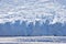 Blue glacier face in silhouette with big crevices