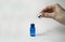 Blue glass bottle with pipette dispenser on white background. Collagen, anti-aging skin care products. Hand holds a